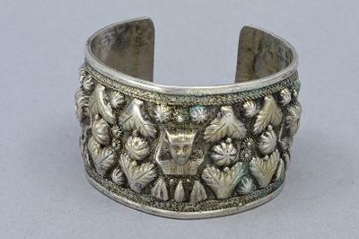 silver bracelet with flowers and birds on it on a gray surface