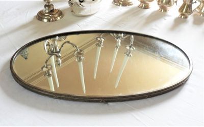 un miroir posé sur une table, dans lequel se reflètent des bougies