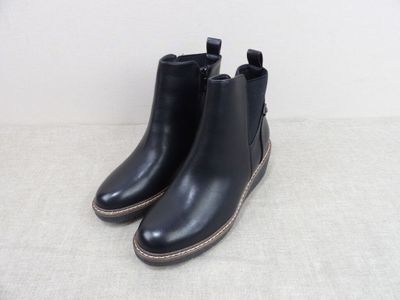 une paire de bottines en cuir noir posées sur une surface blanche
