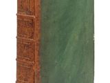 un vieux livre à la couverture verte posé sur une surface blanche