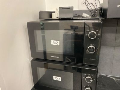 three microwaves stacked on top of each other in a kitchen