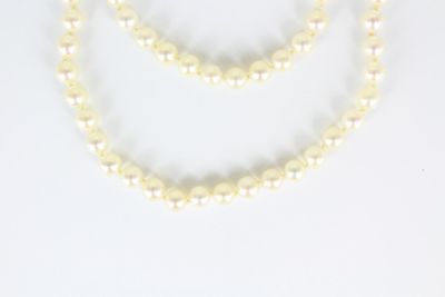 deux rangs de perles blanches avec des fermoirs dorés sur fond blanc