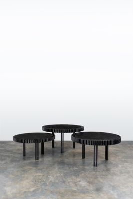 two black tables sitting on top of a cement floor next to a white wall
