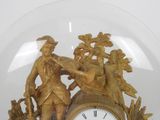 a gold clock with a man and a woman in it