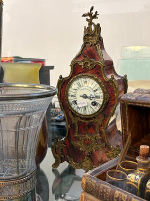 une table en verre sur laquelle se trouvent une horloge et une bouteille de vin