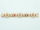 a close up of a gold bracelet with pink stones