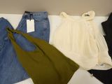 three pairs of jeans, a top, and a tote bag are on a table