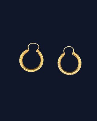 a pair of gold hoop earrings on a black background