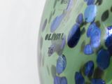 a green vase with blue dots on it sitting on a table