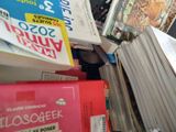 une pile de livres posée sur un bureau, à côté d'un ordinateur