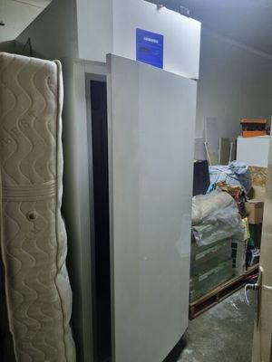 a refrigerator and a bed in a room with a lot of stuff