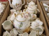 many cups and teapots in a box on the floor