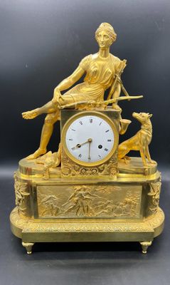 une image représentant une horloge en or surmontée d'une statue de femme