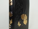 the book is black with gold flowers and leaves on it