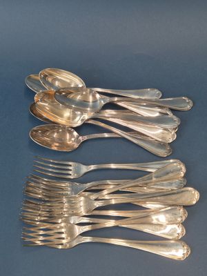 Plusieurs cuillères et fourchettes en argent sont alignées sur un fond bleu