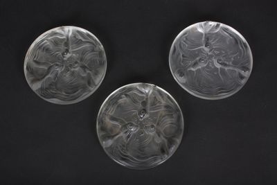 three clear glass plates with designs on them on a black surface