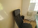 a black office chair next to a desk in a small room