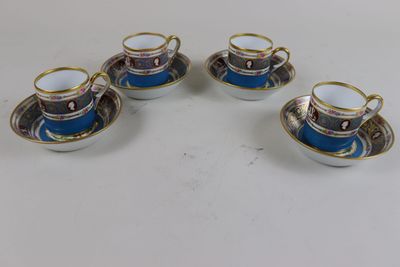 four cups and saucers are sitting on a white table