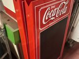 a red coca cola cooler sitting on the floor in a room