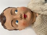 a close up of a doll with blue eyes and a sweater