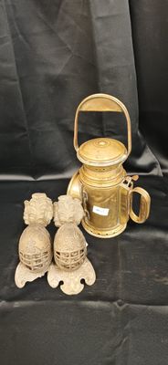 une théière en or et deux petites figurines posées sur un tissu noir