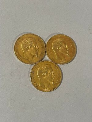 trois pièces d'or posées l'une à côté de l'autre sur une surface blanche