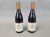 two bottles of red wine sitting next to each other on a table