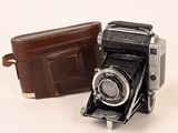un portefeuille en cuir marron à côté d'un vieil appareil photo