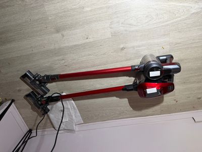 un aspirateur rouge muni d'un cordon d'alimentation et branché sur une prise murale
