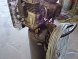 a small air compressor sitting in a garage with a hose