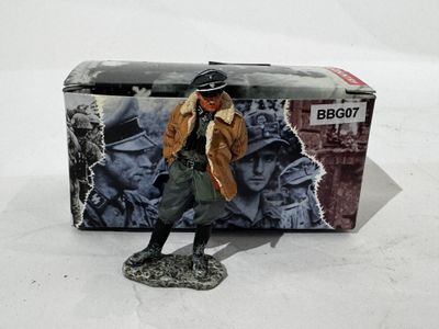 toy figurine of a man in a trench coat and hat standing in front of a box