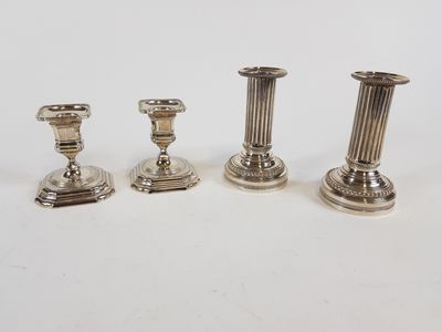 trois bougeoirs en argent posés sur une table blanche