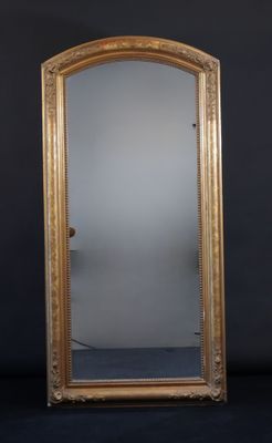 un miroir au cadre doré ouvragé posé contre un mur noir