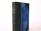 un vieux livre à la couverture bleue posé sur une surface blanche