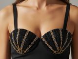 a woman wearing a black bikini top with gold beads on it