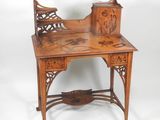 an image of a wooden desk with a carved top and drawers