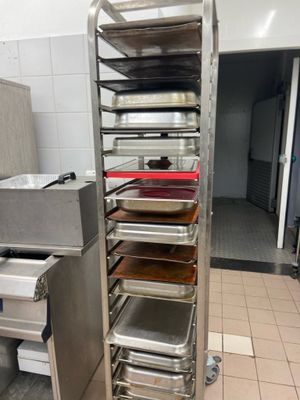 several trays of food are stacked on a metal rack in a kitchen