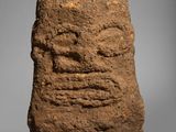 a stone head on a stand with a gray background