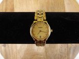 une montre en or posée sur un anneau noir, sur une table en bois