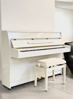 a white piano sitting in a living room next to a couch