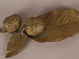 brass figurines of leaves and acorns on a white surface