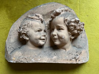 two statues of two children on a green surface