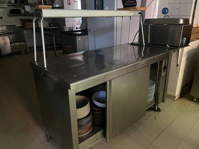 une cuisine équipée d'un plan de travail en inox et d'un micro-ondes