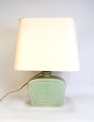 a green table lamp with a white shade on top of it