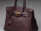 a brown leather handbag with a gold lock on the handle