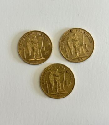 three gold coins sitting next to each other on a white surface