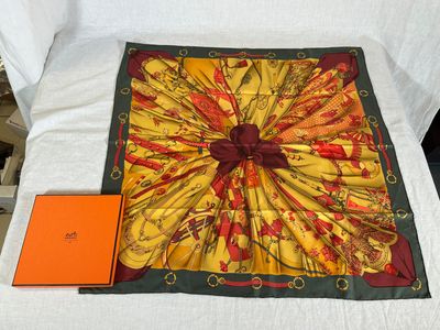 une écharpe jaune et rouge posée sur un lit, à côté d'un livre orange