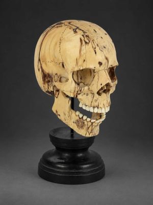a carved skull head on a black stand