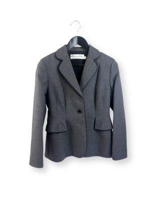 une veste grise suspendue à un cintre sur un mur blanc