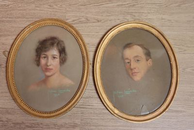 two framed portraits of a woman and a man on a table